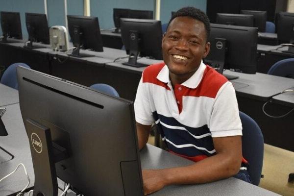 smiling male student sitting at a computer desk