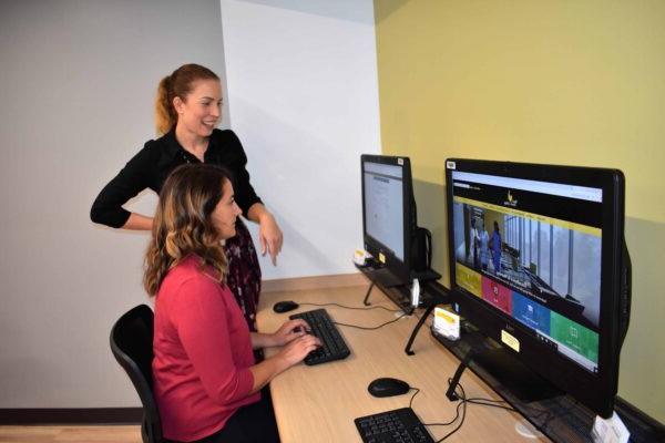 金融援助 director helping a student sitting at a computer